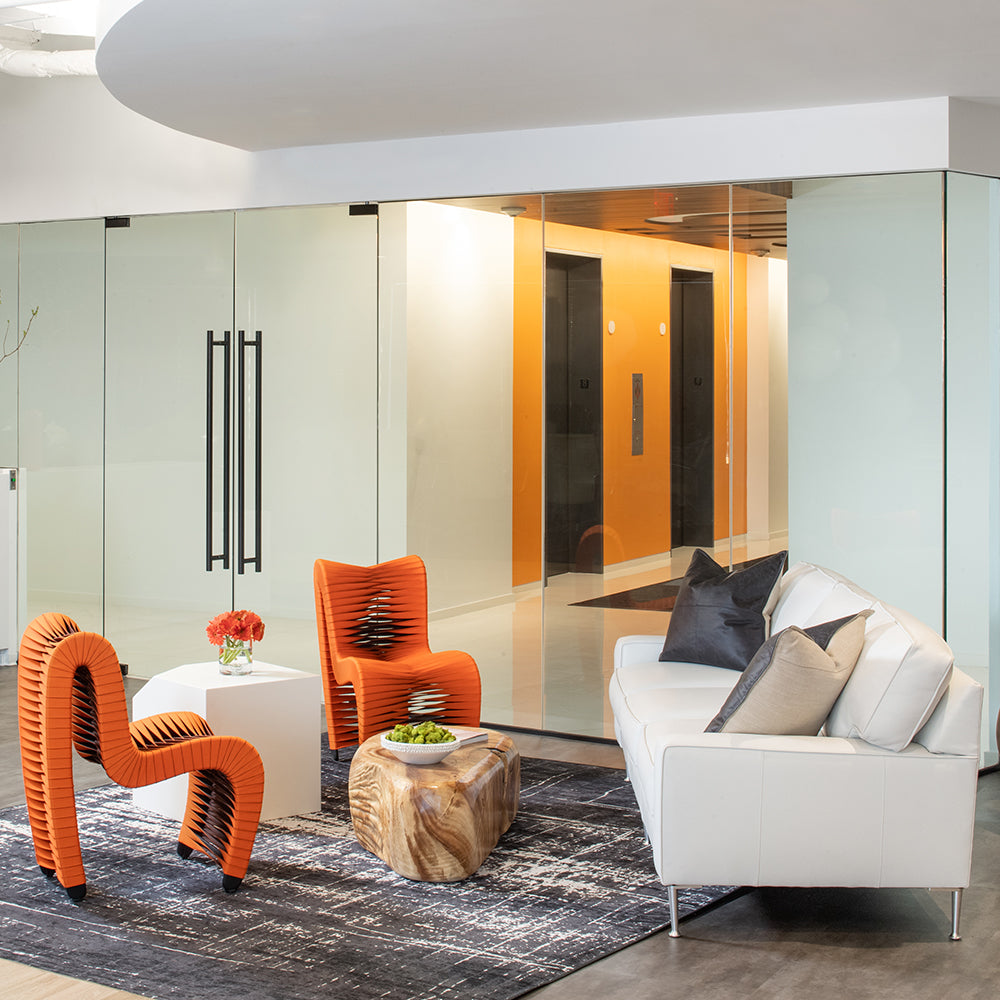 Contemporary office waiting room with orange chairs and white leather sofa - Jamie Merida Interiors