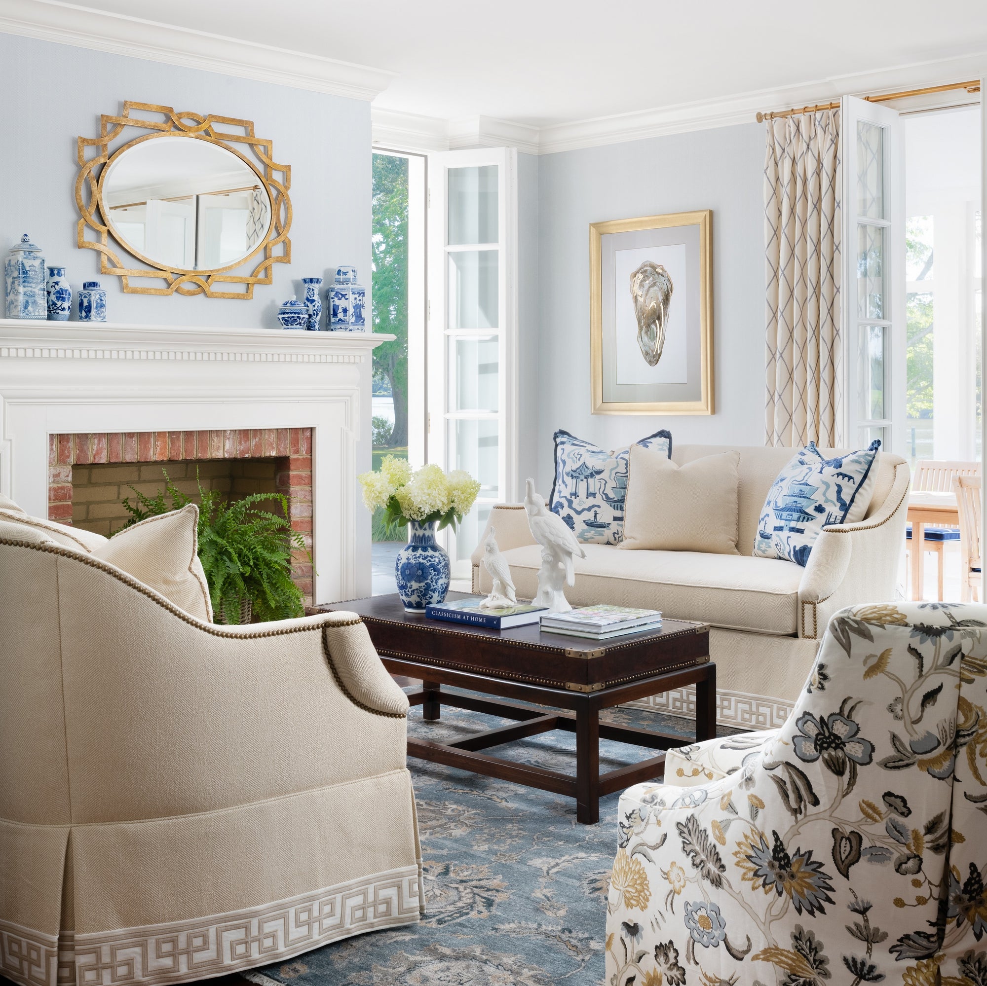 Traditional living room with blue walls and accents, neutral furniture, and natural light. Design by Jamie Merida Interiors.